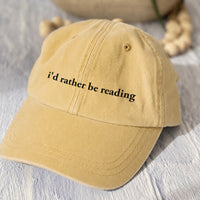 May include an I’d Rather Be Reading Pigment-Dyed Cap featuring a book lover statement on a casual pigment-dyed baseball cap.
