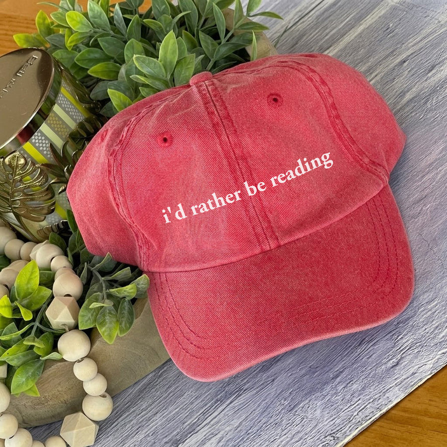 May include an I’d Rather Be Reading Pigment-Dyed Cap featuring a book lover statement on a casual pigment-dyed baseball cap.