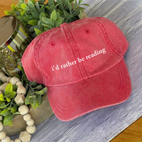 May include an I’d Rather Be Reading Pigment-Dyed Cap featuring a book lover statement on a casual pigment-dyed baseball cap.