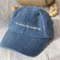 May include an I’d Rather Be Reading Pigment-Dyed Cap featuring a book lover statement on a casual pigment-dyed baseball cap.