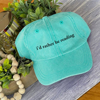 May include an I’d Rather Be Reading Pigment-Dyed Cap featuring a book lover statement on a casual pigment-dyed baseball cap.