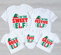 May include a toddler Christmas tee with a playful elf graphic printed on the front, presented on a plain background.