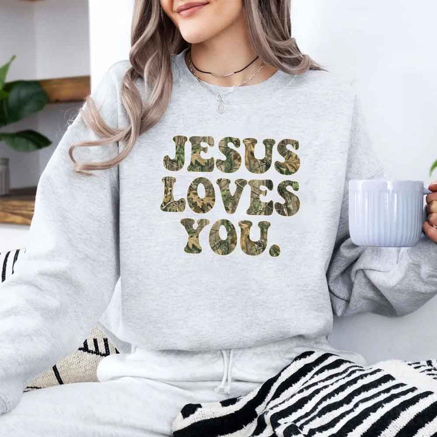 May include Jesus Loves You camouflage sweatshirt with Christian faith graphic design and relaxed unisex fit