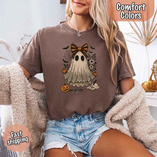 May include lace ghost Halloween graphic with black eyes, orange striped bow, pumpkins, spider web, bats, flowers, and open spell book – spooky vintage shirt design.