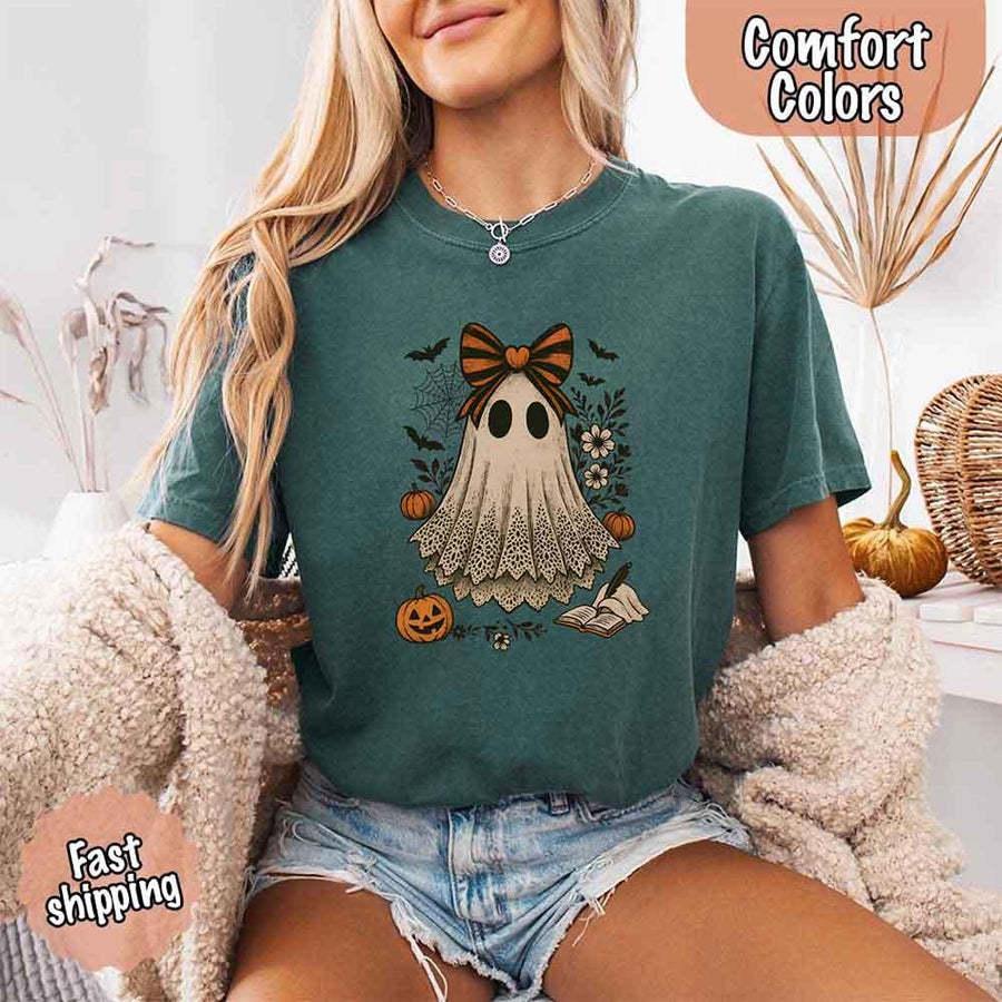 May include lace ghost Halloween graphic with black eyes, orange striped bow, pumpkins, spider web, bats, flowers, and open spell book – spooky vintage shirt design.