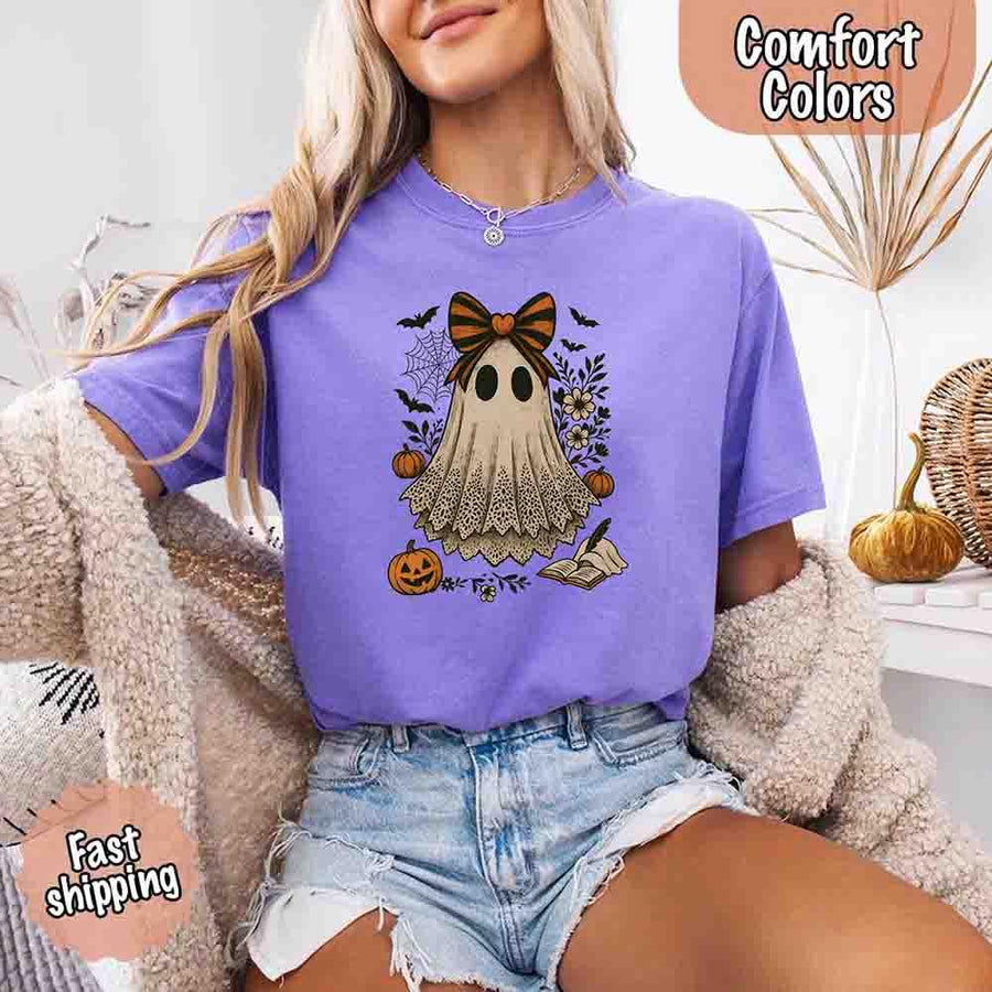 May include lace ghost Halloween graphic with black eyes, orange striped bow, pumpkins, spider web, bats, flowers, and open spell book – spooky vintage shirt design.