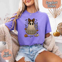 May include lace ghost Halloween graphic with black eyes, orange striped bow, pumpkins, spider web, bats, flowers, and open spell book – spooky vintage shirt design.