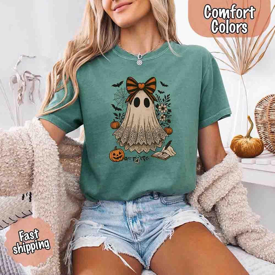 May include lace ghost Halloween graphic with black eyes, orange striped bow, pumpkins, spider web, bats, flowers, and open spell book – spooky vintage shirt design.