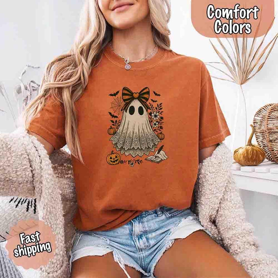 May include lace ghost Halloween graphic with black eyes, orange striped bow, pumpkins, spider web, bats, flowers, and open spell book – spooky vintage shirt design.