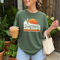 May include a Lake Ontario Comfort Colors T-Shirt featuring a lakeside-inspired graphic design for casual everyday wear.