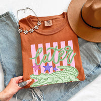 May include a Later Alligator Comfort Colors Tee featuring a playful alligator-inspired statement design on a casual short-sleeve shirt.