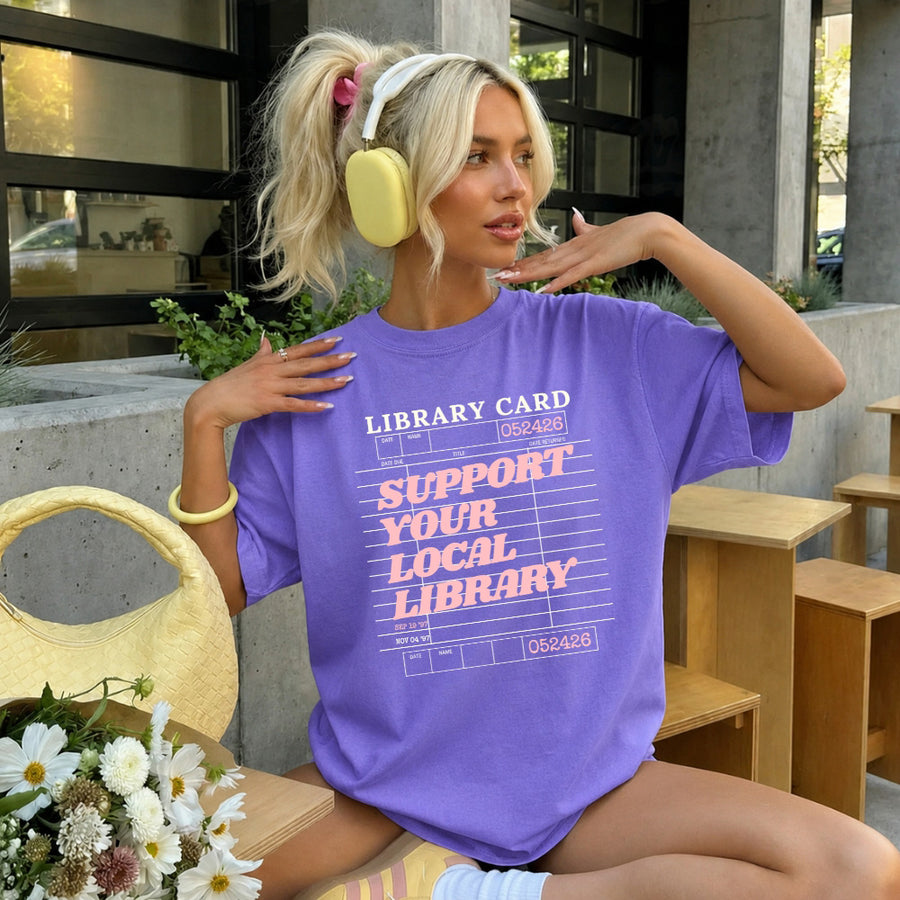 May include a Support Your Local Library Comfort Colors T-Shirt featuring a classic library-inspired statement design.