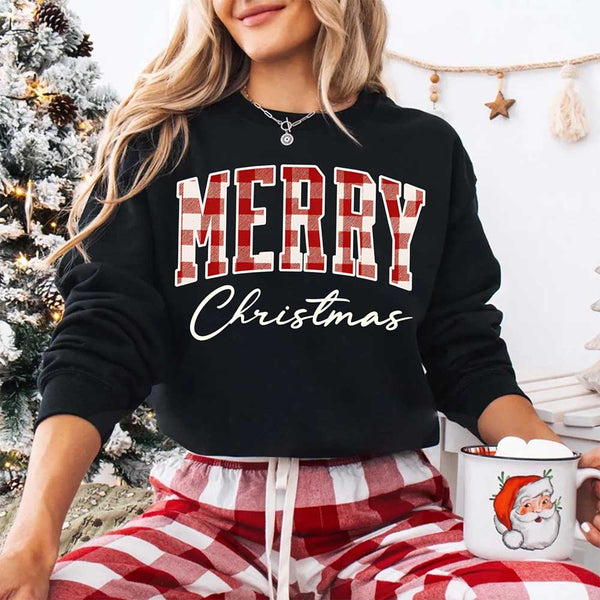 May include a close view of the words “Merry Christmas” printed on fabric, with the top word in a red and black buffalo plaid pattern and the script below in clean black lettering.