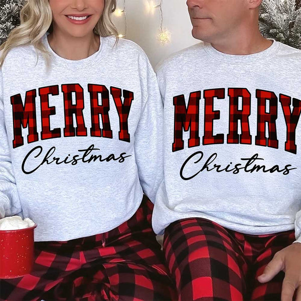 May include a close view of the words “Merry Christmas” printed on fabric, with the top word in a red and black buffalo plaid pattern and the script below in clean black lettering.