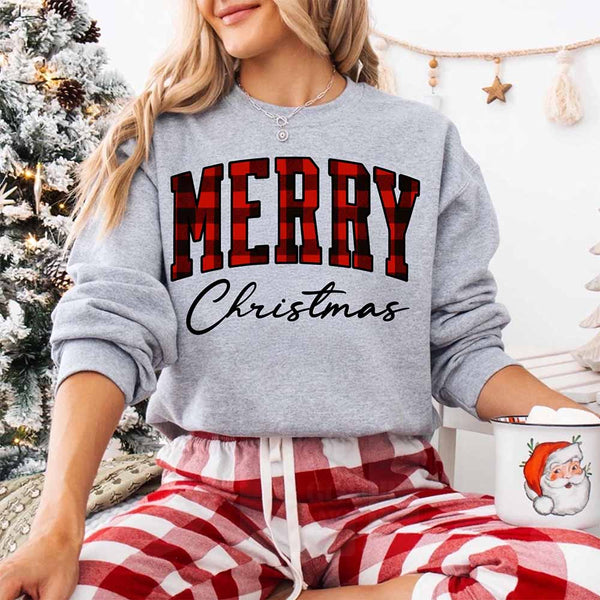 May include a close view of the words “Merry Christmas” printed on fabric, with the top word in a red and black buffalo plaid pattern and the script below in clean black lettering.