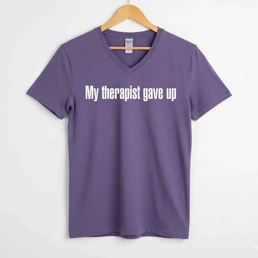 May include a V-neck T-shirt with the humorous phrase “My Therapist Gave Up” displayed on the front.