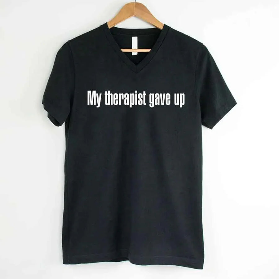May include a V-neck T-shirt with the humorous phrase “My Therapist Gave Up” displayed on the front.