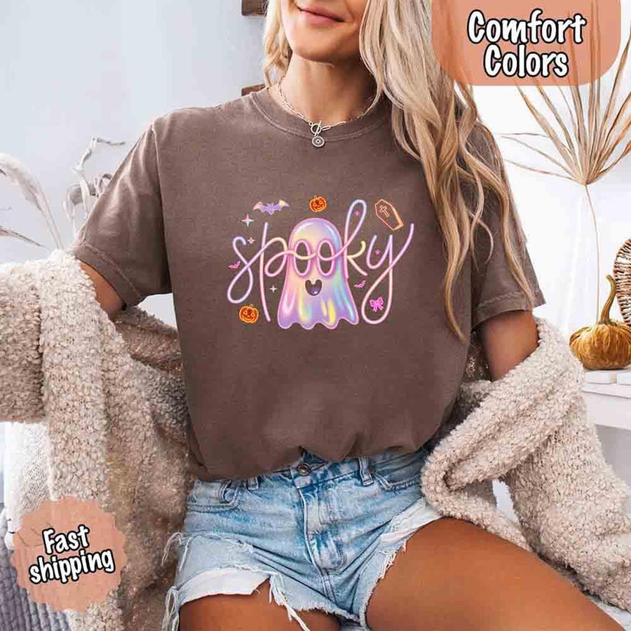 May include holographic ghost with happy face, pastel neon spooky text, pumpkins, bats, coffin, bow, and stars – trendy Halloween graphic tee design.