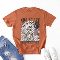 Nightmare Before Coffee skeleton graphic tee featuring skeleton holding a pumpkin coffee mug with steam, bats, and checkered background – funny Halloween coffee shirt.