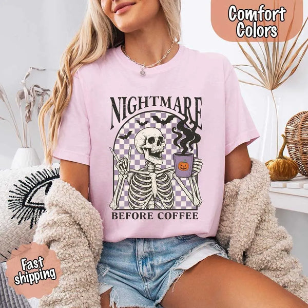 Nightmare Before Coffee skeleton graphic tee featuring skeleton holding a pumpkin coffee mug with steam, bats, and checkered background – funny Halloween coffee shirt.