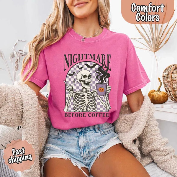 Nightmare Before Coffee skeleton graphic tee featuring skeleton holding a pumpkin coffee mug with steam, bats, and checkered background – funny Halloween coffee shirt.
