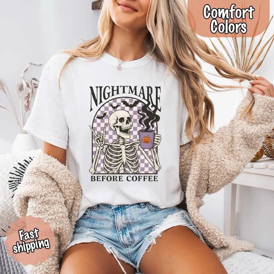 Nightmare Before Coffee skeleton graphic tee featuring skeleton holding a pumpkin coffee mug with steam, bats, and checkered background – funny Halloween coffee shirt.