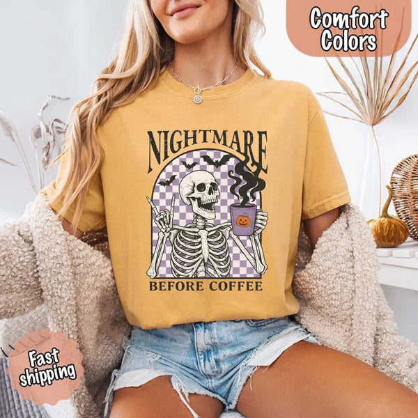 Nightmare Before Coffee skeleton graphic tee featuring skeleton holding a pumpkin coffee mug with steam, bats, and checkered background – funny Halloween coffee shirt.