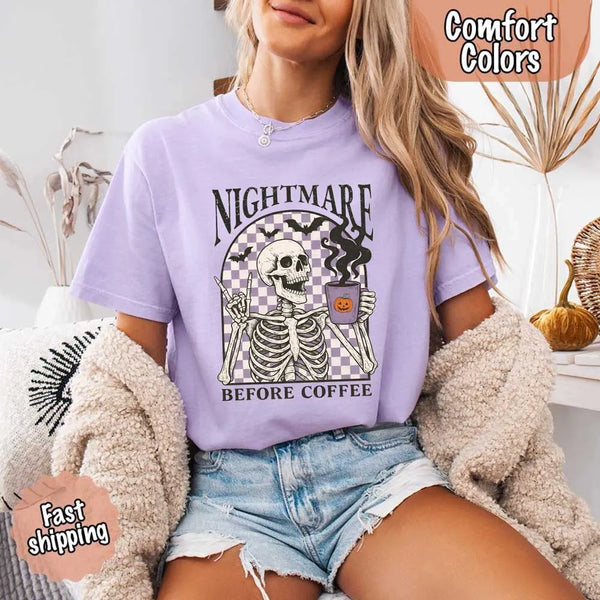 Nightmare Before Coffee skeleton graphic tee featuring skeleton holding a pumpkin coffee mug with steam, bats, and checkered background – funny Halloween coffee shirt.