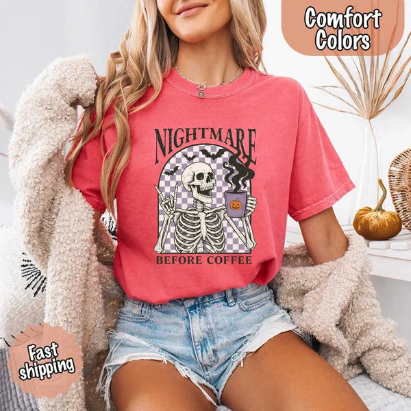 Nightmare Before Coffee skeleton graphic tee featuring skeleton holding a pumpkin coffee mug with steam, bats, and checkered background – funny Halloween coffee shirt.