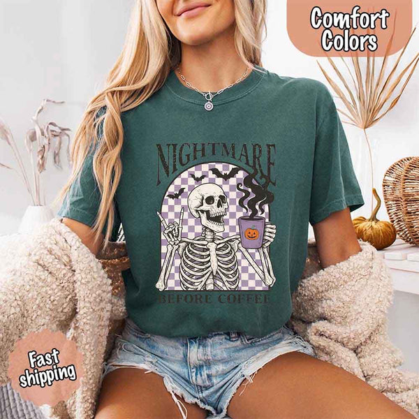 Nightmare Before Coffee skeleton graphic tee featuring skeleton holding a pumpkin coffee mug with steam, bats, and checkered background – funny Halloween coffee shirt.