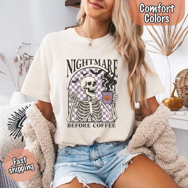 Nightmare Before Coffee skeleton graphic tee featuring skeleton holding a pumpkin coffee mug with steam, bats, and checkered background – funny Halloween coffee shirt.