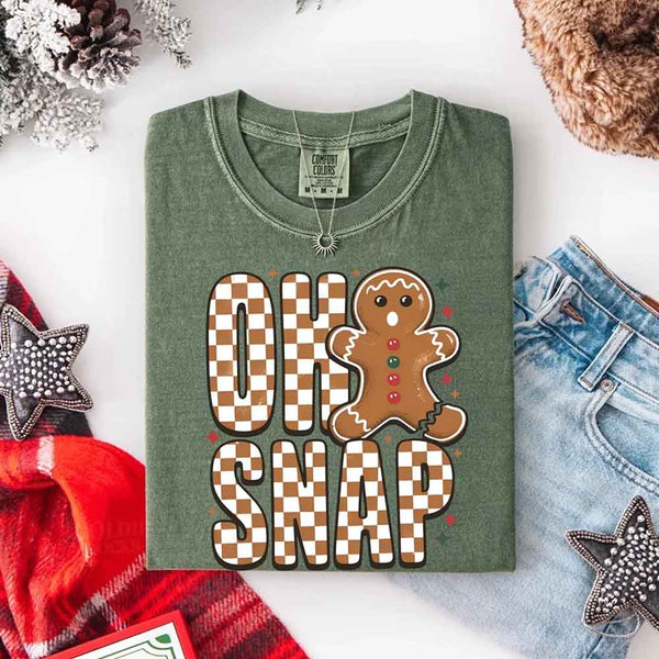 May include a garment-dyed Comfort Colors tee featuring a playful broken gingerbread figure with the phrase “Oh Snap” on the front.