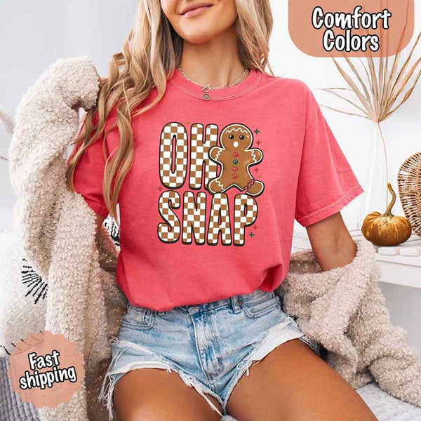 May include a garment-dyed Comfort Colors tee featuring a playful broken gingerbread figure with the phrase “Oh Snap” on the front.