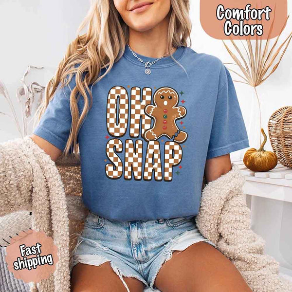 May include a garment-dyed Comfort Colors tee featuring a playful broken gingerbread figure with the phrase “Oh Snap” on the front.