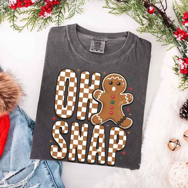 May include a garment-dyed Comfort Colors tee featuring a playful broken gingerbread figure with the phrase “Oh Snap” on the front.