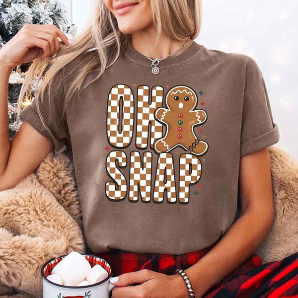 May include a garment-dyed Comfort Colors tee featuring a playful broken gingerbread figure with the phrase “Oh Snap” on the front.