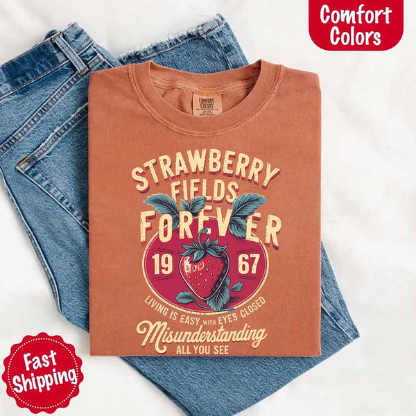 May include vintage-style artwork with a large strawberry and bold text that reads “Strawberry Fields Forever 1967,” along with the phrases “Living is easy with eyes closed” and “Misunderstanding all you see,” inspired by nostalgic and psychedelic themes.