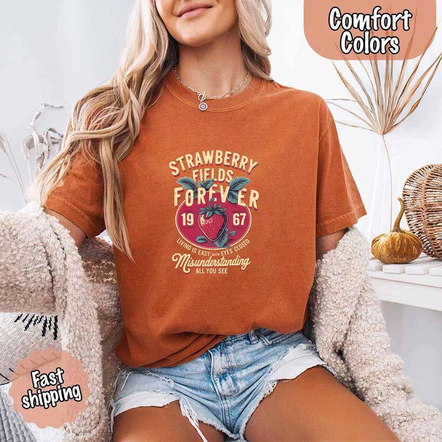 May include vintage-style artwork with a large strawberry and bold text that reads “Strawberry Fields Forever 1967,” along with the phrases “Living is easy with eyes closed” and “Misunderstanding all you see,” inspired by nostalgic and psychedelic themes.