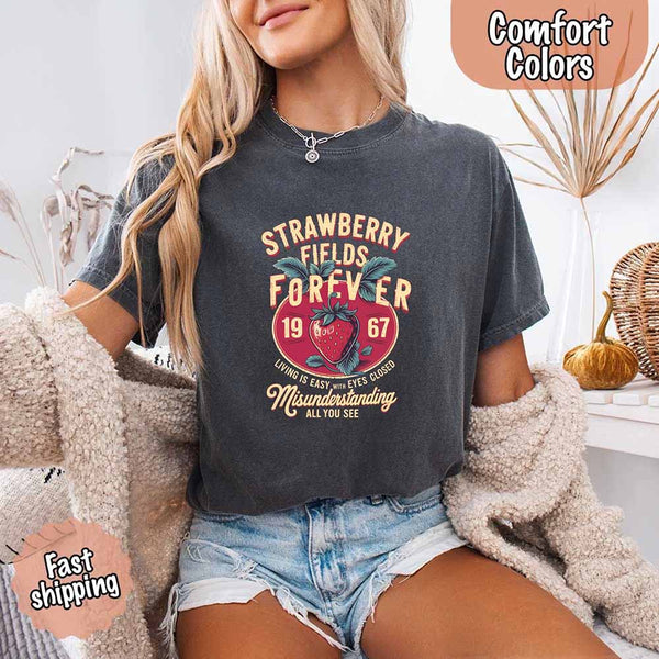 May include vintage-style artwork with a large strawberry and bold text that reads “Strawberry Fields Forever 1967,” along with the phrases “Living is easy with eyes closed” and “Misunderstanding all you see,” inspired by nostalgic and psychedelic themes.