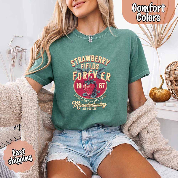 May include vintage-style artwork with a large strawberry and bold text that reads “Strawberry Fields Forever 1967,” along with the phrases “Living is easy with eyes closed” and “Misunderstanding all you see,” inspired by nostalgic and psychedelic themes.