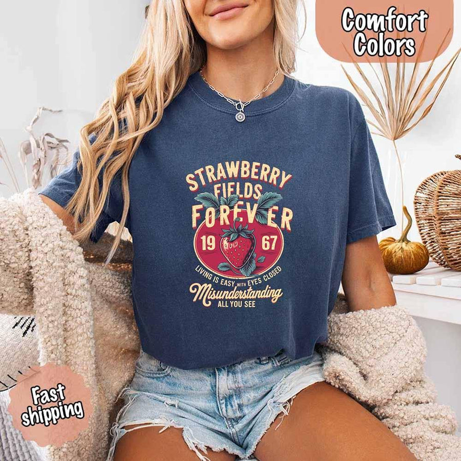 May include vintage-style artwork with a large strawberry and bold text that reads “Strawberry Fields Forever 1967,” along with the phrases “Living is easy with eyes closed” and “Misunderstanding all you see,” inspired by nostalgic and psychedelic themes.