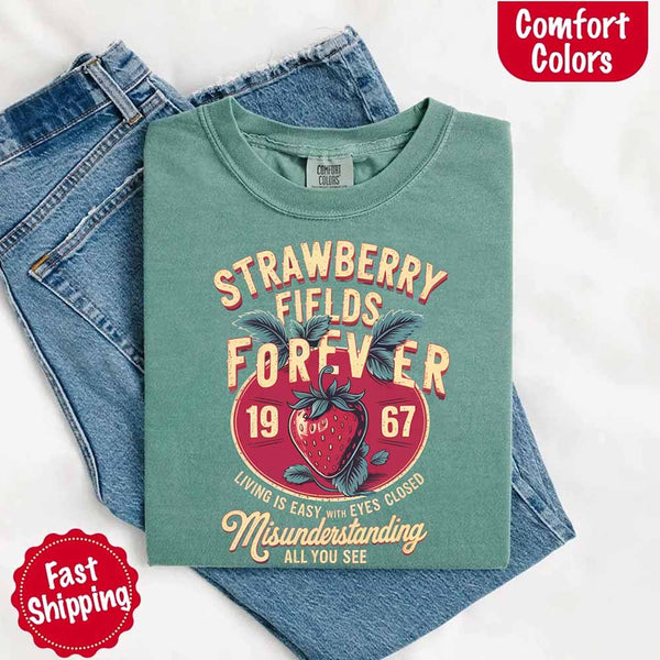 May include vintage-style artwork with a large strawberry and bold text that reads “Strawberry Fields Forever 1967,” along with the phrases “Living is easy with eyes closed” and “Misunderstanding all you see,” inspired by nostalgic and psychedelic themes.
