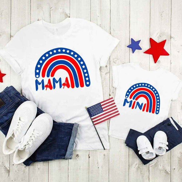 Two white t-shirts with patriotic designs on a wooden surface with jeans and shoes.