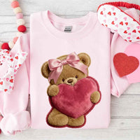 May include a crewneck sweatshirt with a plush teddy Valentine design featuring a furry-look 3D printed effect.