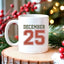 May include a glossy ceramic mug with a retro December 25 Christmas design in traditional holiday colors.
