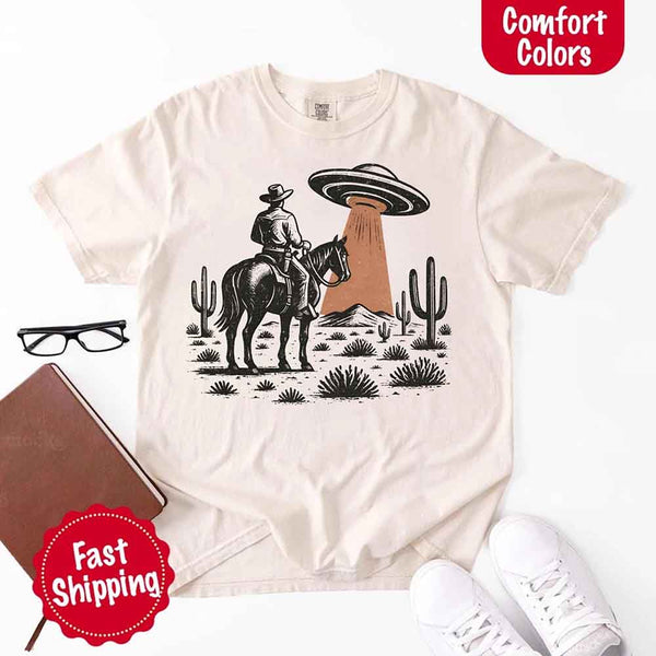 Retro cowboy and horse graphic with UFO beaming light in desert landscape with cacti – western alien mashup design