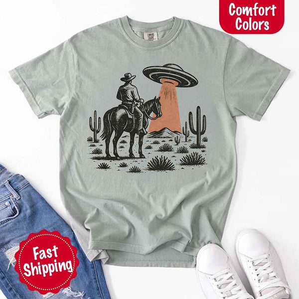 Retro cowboy and horse graphic with UFO beaming light in desert landscape with cacti – western alien mashup design