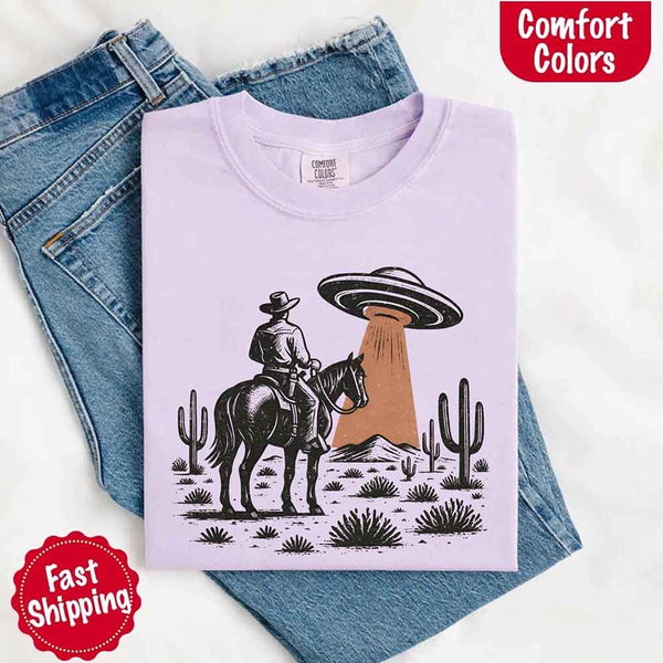 Retro cowboy and horse graphic with UFO beaming light in desert landscape with cacti – western alien mashup design