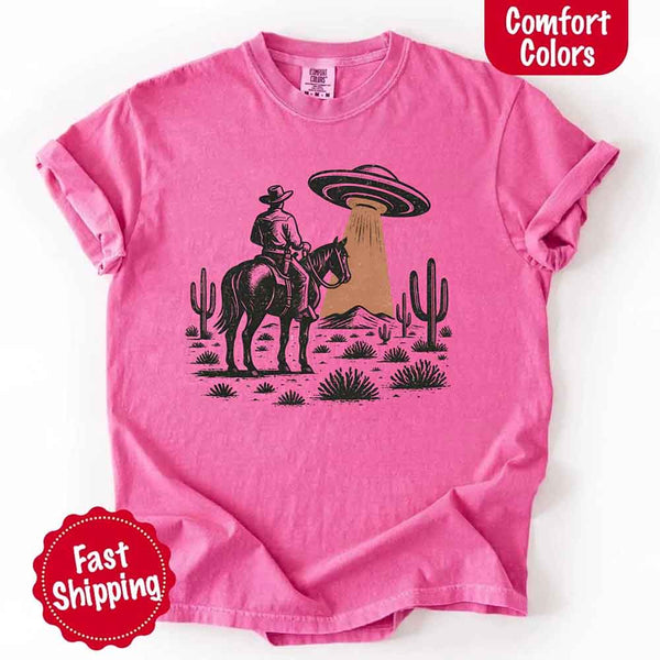 Retro cowboy and horse graphic with UFO beaming light in desert landscape with cacti – western alien mashup design
