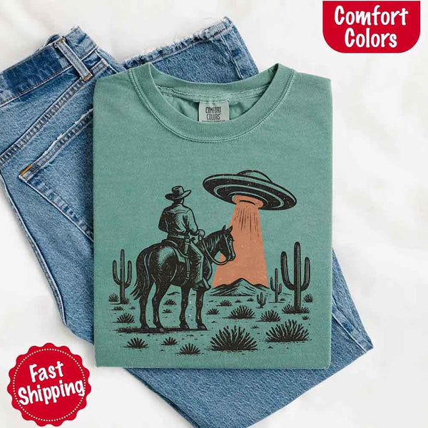 Retro cowboy and horse graphic with UFO beaming light in desert landscape with cacti – western alien mashup design